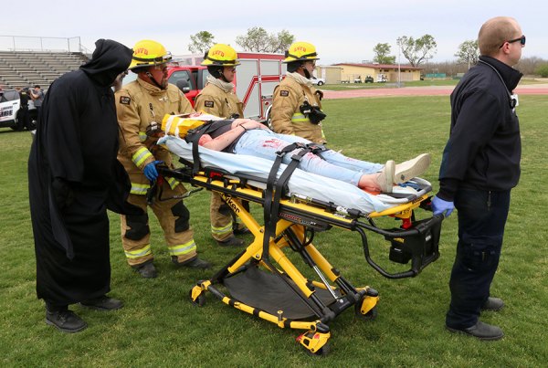 The Grim Reaper assists Lemoore Firefighters as they deliver an injured Mia Raber to a waiting helicopter that will deliver her to Adventist Hospital. It was part of a program entitled "Every 15 Minutes" that played to LHS students Thursday afternoon.